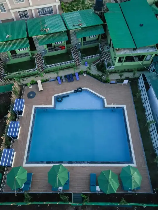 Aerial view of the pool with green umbrellas and cottages